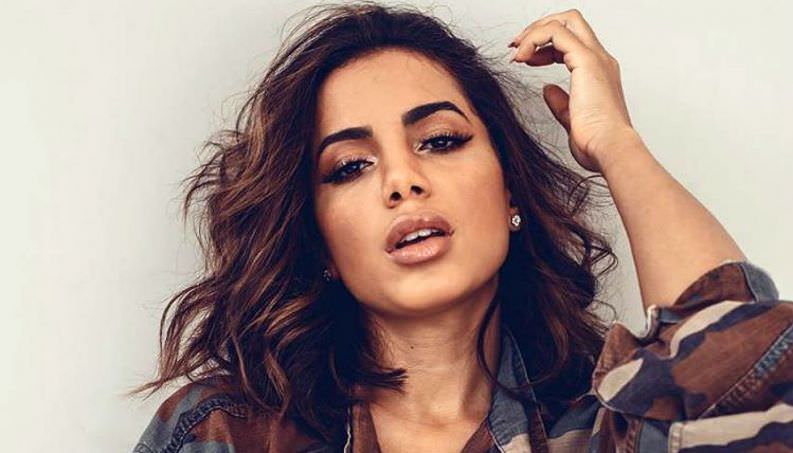 Anitta renova o bronze e deixa os seios à mostra na praia