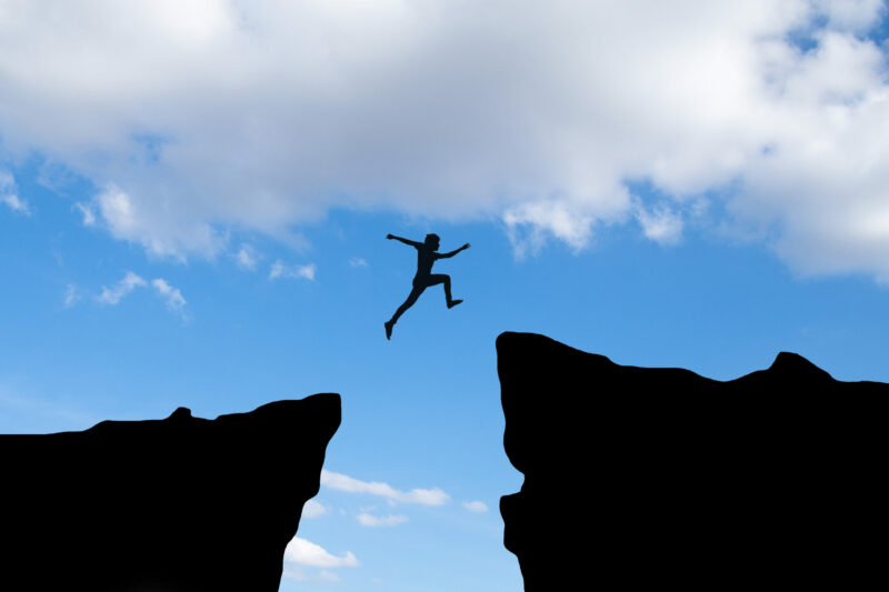 courage-man-jump-through-the-gap-between-hill-business-concept